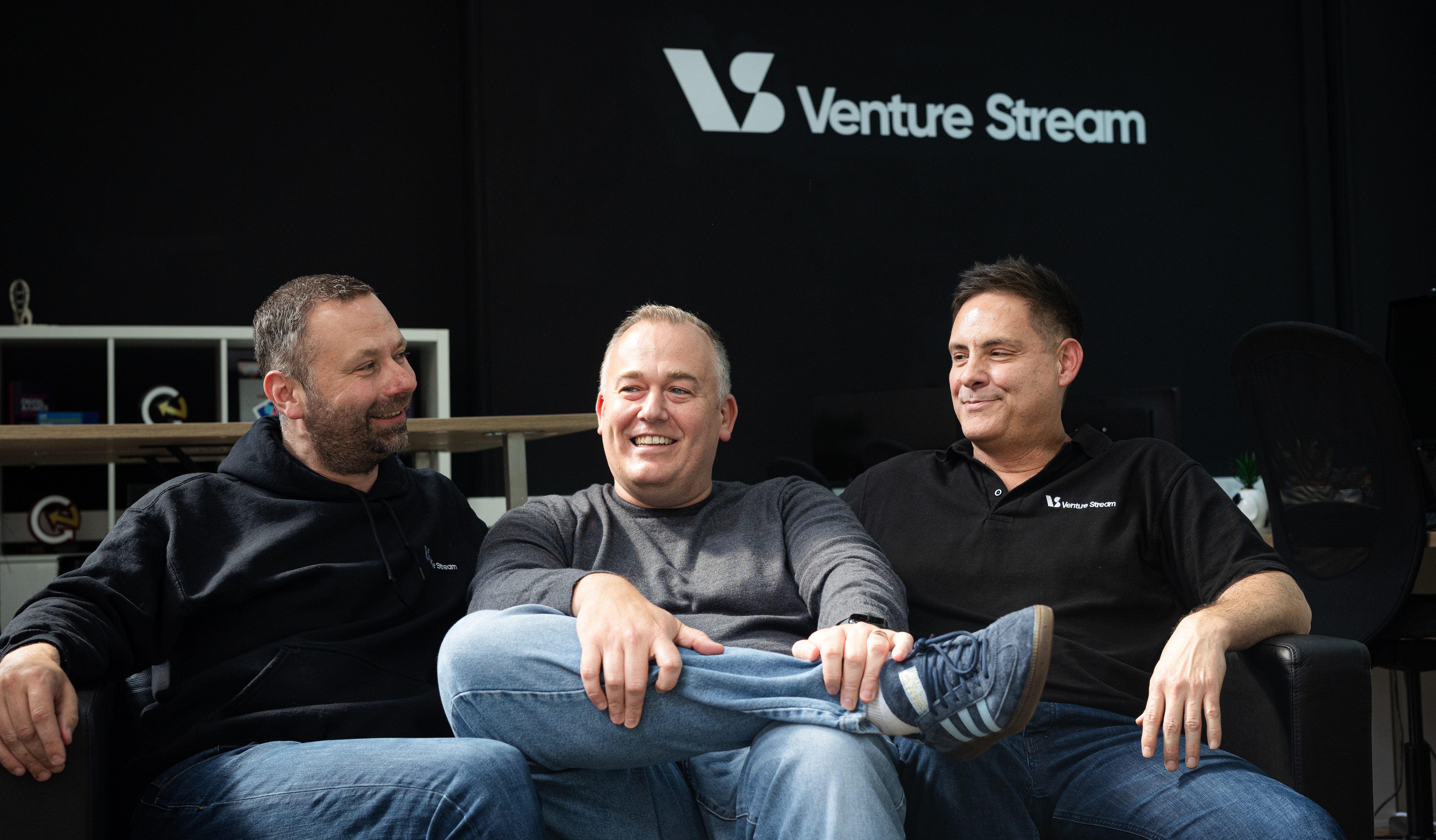 Three gentlemen sitting on a sofa, in conversation. One wears a black hoodie, one where's a grey jumper, one wears a black t-shirt.Three gentlemen sitting on a sofa, in conversation. One wears a black hoodie, one where's a grey jumper, one wears a black t-shirt.Three gentlemen sitting on a sofa, in conversation. One wears a black hoodie, one where's a grey jumper, one wears a black t-shirt.